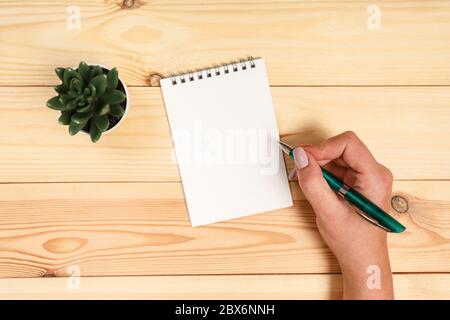 Moderner Arbeitsplatz mit Smartphone, Papier, Notebook und weiblichen Händen auf Holzhintergrund. Draufsicht. Stockfoto