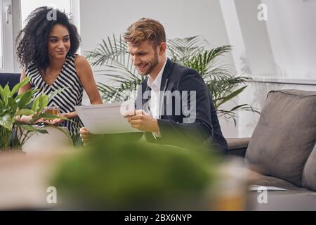 Fröhlicher Mann, der in seinen Händen durch Dokumente schaut Stockfoto