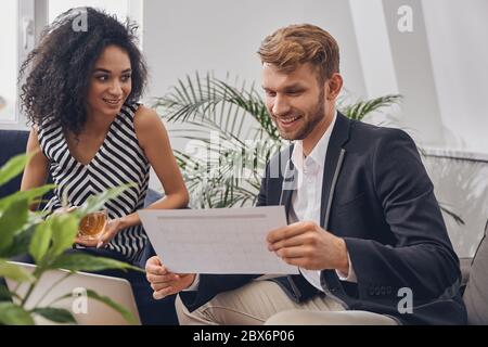 Lächelnde Geschäftsfrau, die ihren Kollegen ansieht Stockfoto