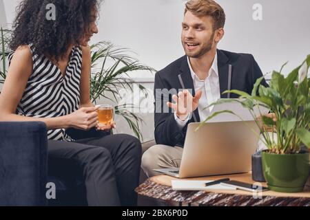 Dunkelhaarige Dame lächelt einen zufrieden Geschäftsmann an Stockfoto