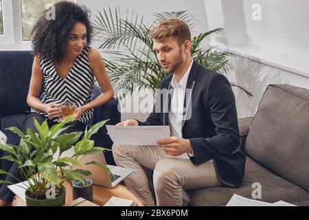 Erfreut Frau, die ihrem männlichen Mitarbeiter zuhört Stockfoto