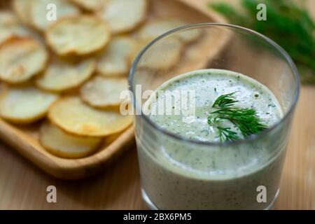 Dill und Sauerrahm Dip für hausgemachte Kartoffelchips vegan: Gesunder Snack mit Dill, Tahini, Wasser, Essig und Zitronensaft im Glas. Dünne Scheiben Stockfoto
