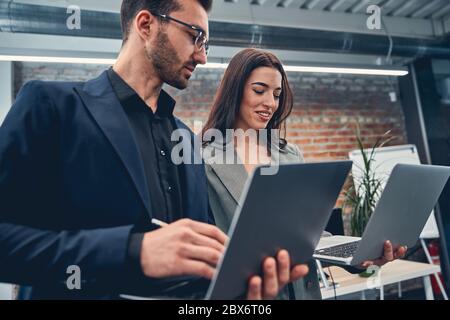 Zufriedene Geschäftsleute, die sich Laptops angeschaut haben Stockfoto