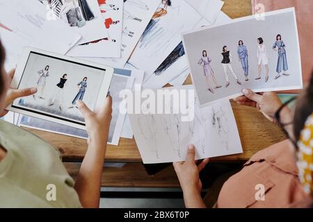 Zwei Modedesigner diskutieren ihre Skizzen von trendigen Kleidungsstücken für ihre neue saisonale Kollektion beim Start-up Meeting Stockfoto