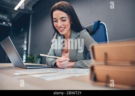 Lachende Dame, die im Büro am Laptop arbeitet Stockfoto