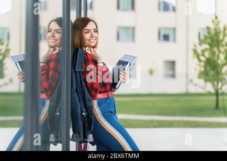 Portrait eines schönen Studenten, der eine Jacke auf der Schulter hält und Bücher in den Händen hält Stockfoto