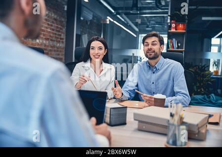 Kollegen sitzen am Bürotisch mit Laptop und Kaffee Stockfoto