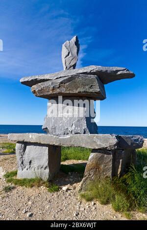 Inukshuk sitzt am Strand der Hudson Bay in Churchill, Manitoba, Kanada. Ein Inukshuk ist ein von Menschen in der Arktis errichtetes Steindenkmal Stockfoto