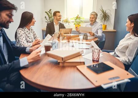 Glückliche junge Kollegen diskutieren neuen Vertrag mit männlichen Chef Stockfoto