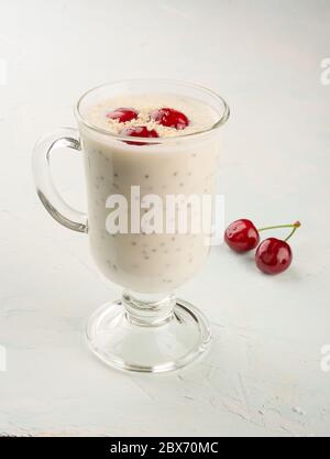 Chia Joghurt Pudding mit Kokosflocken und Kirschenbeeren. Gesunde Ernährung, um Kraft und Gewicht zu reduzieren. Chia und Joghurtpudding im Glas Stockfoto