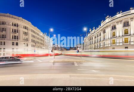 Nachtaufnahme von verschwommenen Straßenbahnen am Schwarzenbergplatz mit Verkehr und nächtblauem Himmel in Wien, Österreich Stockfoto