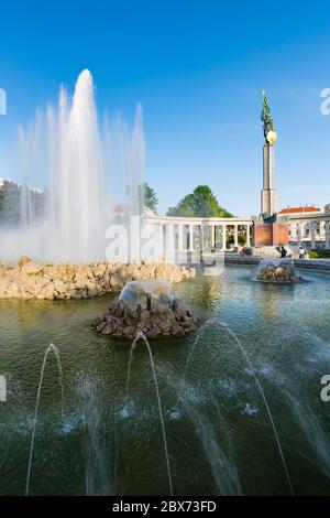 Der Brunnen am Schwarzenbergplatz in Wien, Österreich mit dem sowjetischen Kriegsdenkmal im Hintergrund und blauem Himmel. Stockfoto