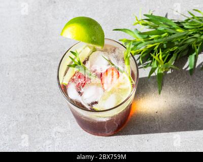Erfrischender Sommercocktail Limonade mit Eis, Limette, Erdbeeren und Estragon Stockfoto
