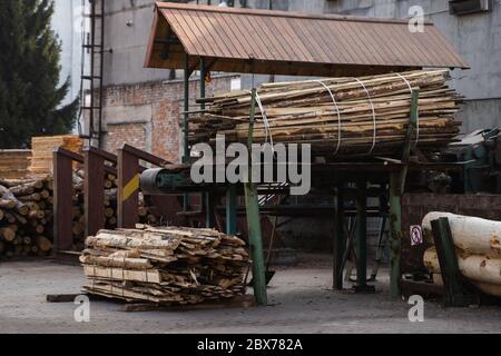 Entfernung der Rinde von den großen Balken auf dem Sägewerk. Die Vorbereitung der hölzernen Balken bis zum Sägen auf der Schnittlinie auf dem Sägewerk. Die Holzindustrie. Ein Haufen von Baumstämmen liegt Stockfoto