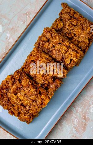 Hafer und Kornflocke Flapjack sitzen auf einem blauen rechteckigen Platte von oben gesehen Stockfoto