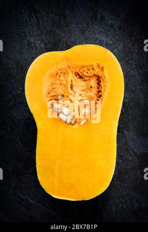 Butternut Kürbis oder Kürbis, in der Mitte geschnitten, Draufsicht über dunklen Stein Hintergrund. Stockfoto