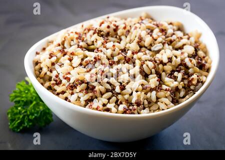 Reis und Quinoa in weißer Schüssel über Schiefer anbraten. Stockfoto