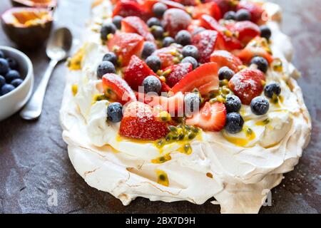 Pawlova-Baiser mit Beeren und Passionsfrucht. Seitenansicht auf Schiefer. Stockfoto