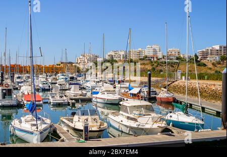 Viele Motorboote und Yachten liegen an einem sonnigen Tag mit blauem Himmel an der Marina in Portimao, der westlichen Algarve, Südportugal Stockfoto