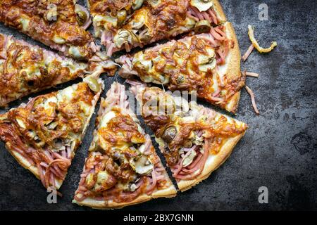 Pizza, in Scheiben geschnitten. Blick von oben auf dunklem Schiefer. Leckere traditionelle italienische capricciosa. Stockfoto