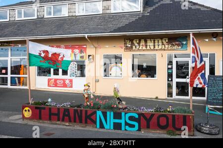 Walisische Flagge, und, Union Jack, Flagge mit Danke NHS, National Health Service, Unterstützung, Poster, Banner, von, Öffentlichkeit, Unterstützung, außerhalb, geschlossen, Sand, Café, Restaurant, dass, ist, geschlossen, aufgrund, Coronavirus, Covid 19, Pandemie, in, Borth, Meer, Urlaub, Resort, Norden, Aberystwyth, Ceredigion hat eine große Anzahl von Einheimischen und Touristen außerhalb Wales zu bleiben. Aber es hat auch eine Wirtschaft mit vielen auf Tourismus, Touristen angewiesen. Stockfoto