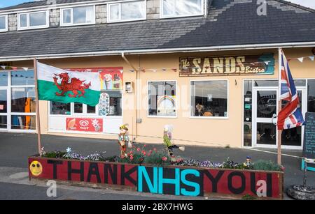 Walisische Flagge, und, Union Jack, Flagge mit Danke NHS, National Health Service, Unterstützung, Poster, Banner, von, Öffentlichkeit, Unterstützung, außerhalb, geschlossen, Sand, Café, Restaurant, dass, ist, geschlossen, aufgrund, Coronavirus, Covid 19, Pandemie, in, Borth, Meer, Urlaub, Resort, Norden, Aberystwyth, Ceredigion hat eine große Anzahl von Einheimischen und Touristen außerhalb Wales zu bleiben. Aber es hat auch eine Wirtschaft mit vielen auf Tourismus, Touristen angewiesen. Stockfoto