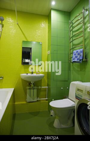 Bad in grün und gelb. Toilettenschüssel, Waschbecken, Waschmaschine, Badewanne. Stockfoto