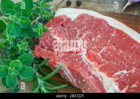 Rohes Rindersteak mit frischen Kräutern, auf Holzbrett. Stockfoto