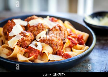 Pappardelle Pasta mit Fleischbällchen und rasierte Parmesan, in schwarzer Schale. Horizontal, Seitenansicht. Stockfoto