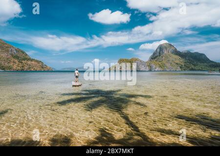 Mann, der auf einem Bambusfloat mit beeindruckender Aussicht auf die Cadlao-Insel bleibt. Palawan, Philippinen. Urlaubskonzept Stockfoto