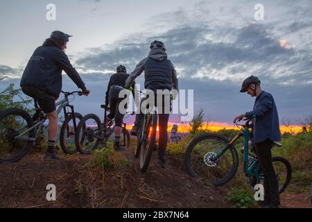 Mountainbiker treffen sich auf dem Hügel bei Sonnenuntergang in Großbritannien Stockfoto