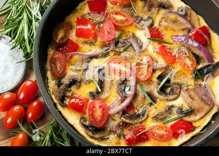 Gemüseomelett in einer Pfanne oder Frypan gekocht. Pilze, Paprika, Baby-Pflaume-Tomaten und rote Zwiebel. Draufsicht. Stockfoto