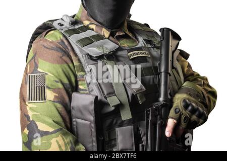 Isoliertes Nahaufnahme-Foto einer männlichen Brust, die in Militärjacke mit automatischem Gewehr und amerikanischem Flaggenabzeichen steht. Stockfoto