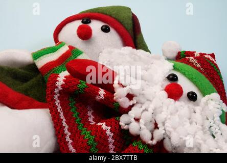 Weihnachtsmann und Schneemann Spielzeug in roten weihnachts-Outfit auf blauem Hintergrund. Stockfoto