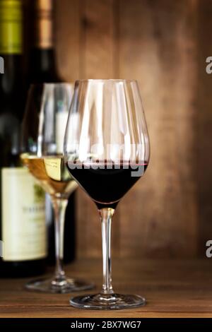 Rot-Weiß-Weingläser und -Flaschen, auf Eichengrund. Stockfoto