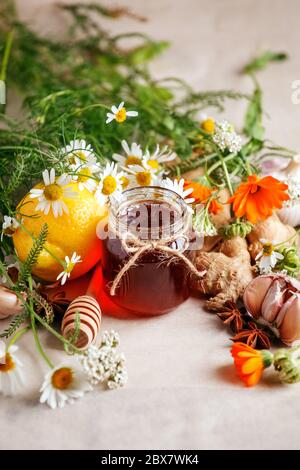 Glas mit Bio-Honig, Zitrone, Knoblauchwurzel, Anis, frischen Blumen Kamille und Ringelblume. Konzept der alternativen Medizin, Homöopathie, saisonale Grippe heiß t Stockfoto