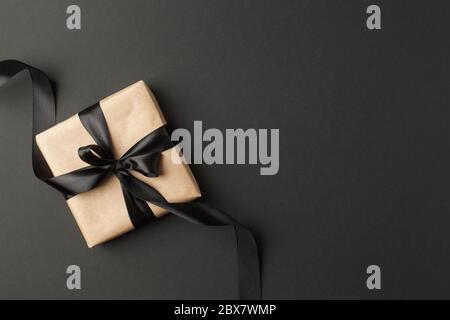 Geschenk oder Geschenk Bastelbox mit schwarzer Schleife auf schwarzer Tischansicht. Wohnung legen Komposition für Geburtstag, Muttertag, schwarz freitag Verkauf, Weihnachten, n Stockfoto