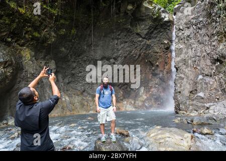 Reiseführer fotografiert Wanderer mit Bart neben Fluss und Wasserfall in Sensoria, tropisches Regenwald-Reservat, Rincon de la Vieja, Provincia de Alajuela Stockfoto