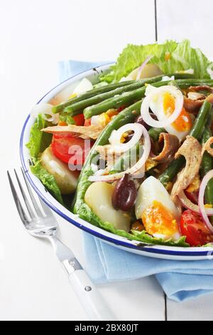 Salat-Nicoise. Thunfisch mit Eiern, Kartoffeln, grünen Bohnen, Tomaten, Sardellen, Zwiebeln und schwarzen Oliven. Mit Vinaigrette-Dressing. Stockfoto
