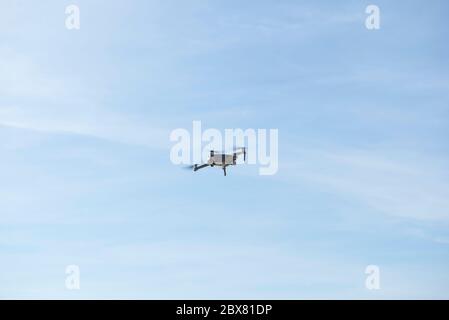 Drohne fliegt in blauem Himmel mit Wolken im Hintergrund. Drohne fliegt über dem Himmel in wolkig-blauem Himmel. Drohne Quad Copter mit hochauflösender digitaler Kamera Stockfoto