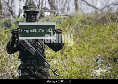 Ein kenianischer Wildlife Service-Wildhüter hält ein Plakat mit der Aufschrift "I Support Ban Plastics" im Lake Nakuru National Park während der Kampagne zum Verbot der einmaligen Verwendung von Plastiktüten. Während des Weltumwelttags begann Kenia mit der Einführung eines Verbots der einmaligen Verwendung von Kunststoff in allen Schutzgebieten. Frühere Plastiktüten Verbot wurde als erfolgreich von vielen gefeiert. Stockfoto