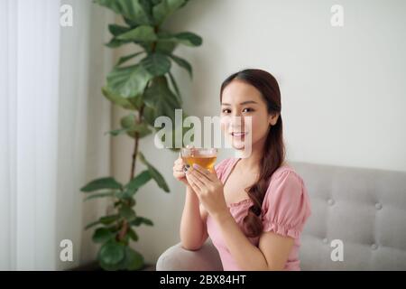 Schöne junge asiatische Frau Tee am Morgen im Wohnzimmer trinken. Stockfoto