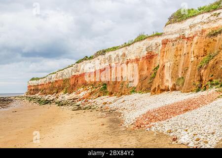 Orangene, rote und weiße Sedimentgesteine am Strand in Hunstanton, Norfolk, East Anglia, Großbritannien. Stockfoto