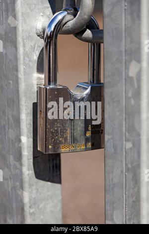 Ein Vorhängeschloss, das um eine Zaunöffnung befestigt ist Stockfoto