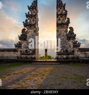 Eine unerkennbare Frau, die am Eingang Pura Luhur Lempuyang bei Sonnenuntergang, Bali, Indonesien, betet Stockfoto