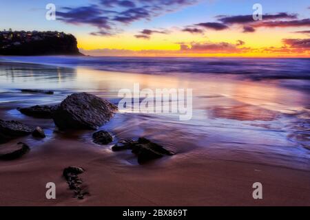 Ruhiger Sandstrand in Sydney an der Pazifikküste bei Sonnenaufgang mit spektakulären Farben. Stockfoto