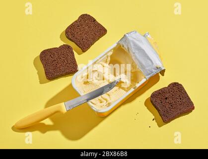 Roggenbrot und Butter mit langen Schatten auf gelbem Hintergrund Stockfoto