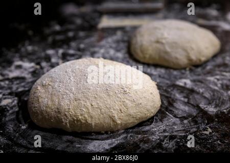 Roggen- und Weizensauerteig-Laib mit hoher Flüssigkeitszufuhr, geformt für einen rustikalen Vollkorn-Sauerteigbrot auf einer bemehlten Oberfläche, Fotoserie Stockfoto