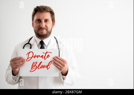 Porträt des männlichen Arztes mit Stethoskop in medizinischer Uniform, das ein weißes Papier hält und auf einem weißen isolierten Hintergrund lächelt Stockfoto
