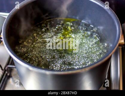 Kochendes Wasser in einem Topf mit Öl, Nahaufnahme - selektiver Fokus Stockfoto